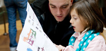 Learn about art: Girl and Man looking at Gallery Map and 'Festival of Light' trail Pamphlet